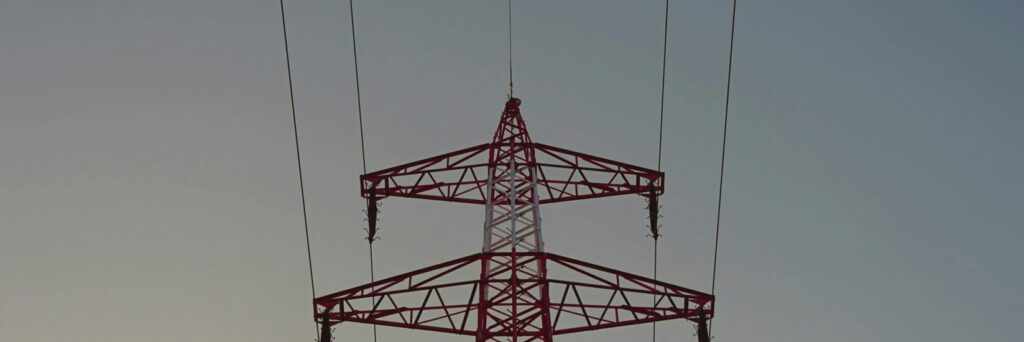 Silhouette of a high voltage transmission tower against a clear dusk sky in Austria.